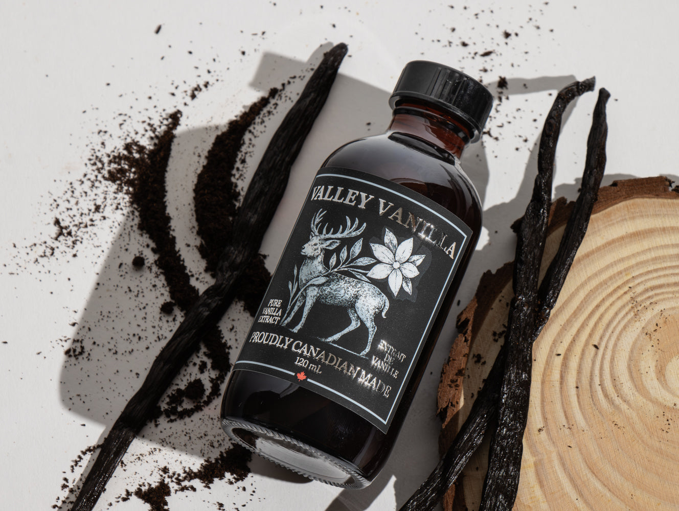 Bottle of Valley Vanilla extract with vanilla beans and coffee grounds on a light background